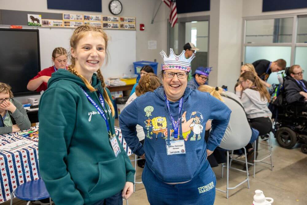 Volunteer and camper wearing paper crown in classroom at Camp ReCreation